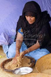 Image du Maroc Professionnelle de  Sous une tente bédouine une femme du Sahara  prépare le couscous durant le grand Moussem de Tan Tan, classé en 2005 patrimoine immatériel humain mondial de l'Unesco. Le Moussem est une sorte de foire annuelle, à la fois économique, culturelle et sociale. Chaque année la majorité des tribus et des grandes familles nomades du désert se retrouvent sur un site désertique "Place de la Tolérance et de la Paix " à la périphérie de Tan Tan où  danse, chants, course de chameaux et fantasia font partie des festivités. , Samedi 18 septembre 2004, ((Photo / Abdeljalil Bounhar)